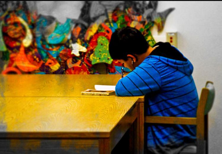 Boy at library table writing