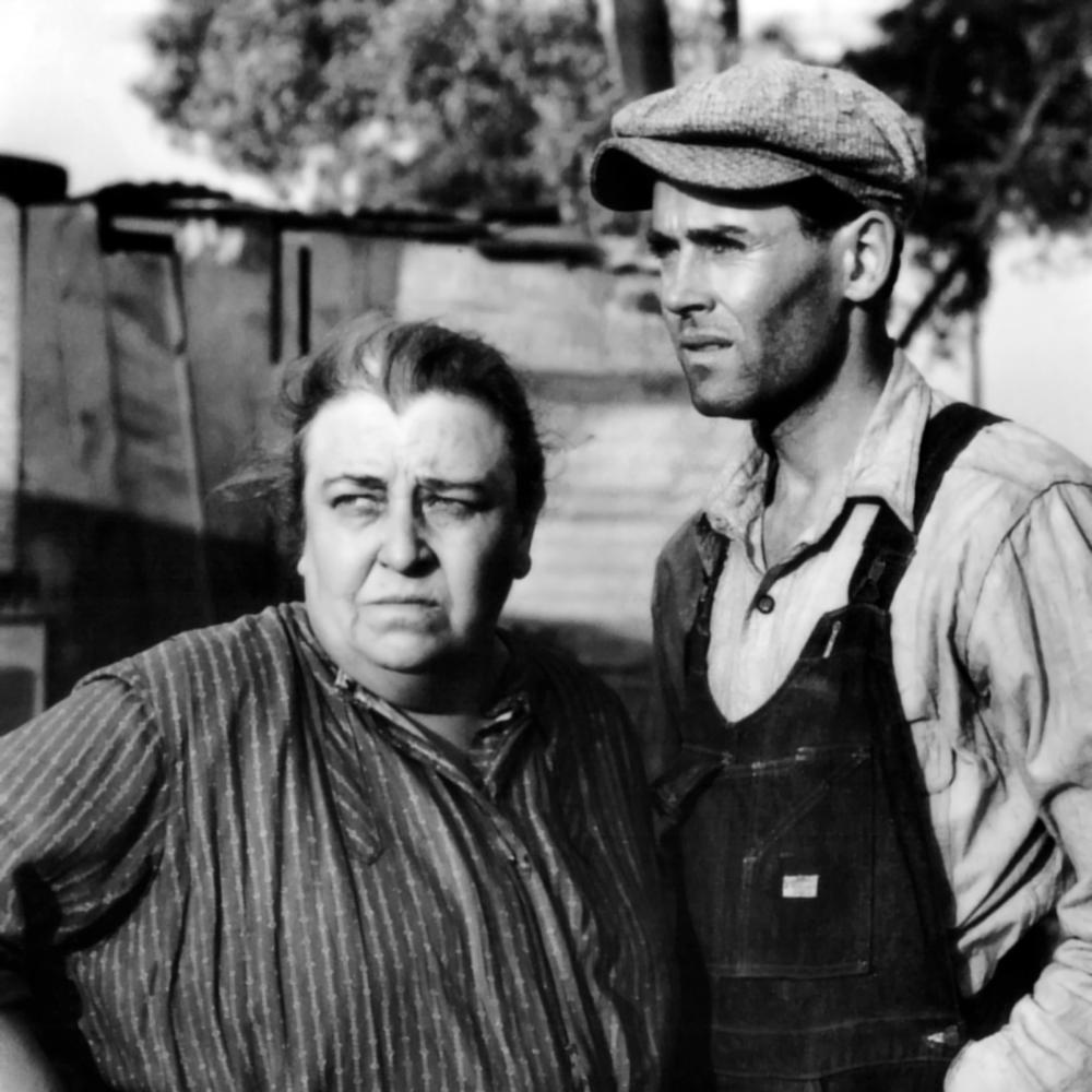 Darwell looks away from Fonda and squints, hands on her hips, while Fonda, wearing a newsboy cap, looks in the same direction and puts his hands in his overall pockets