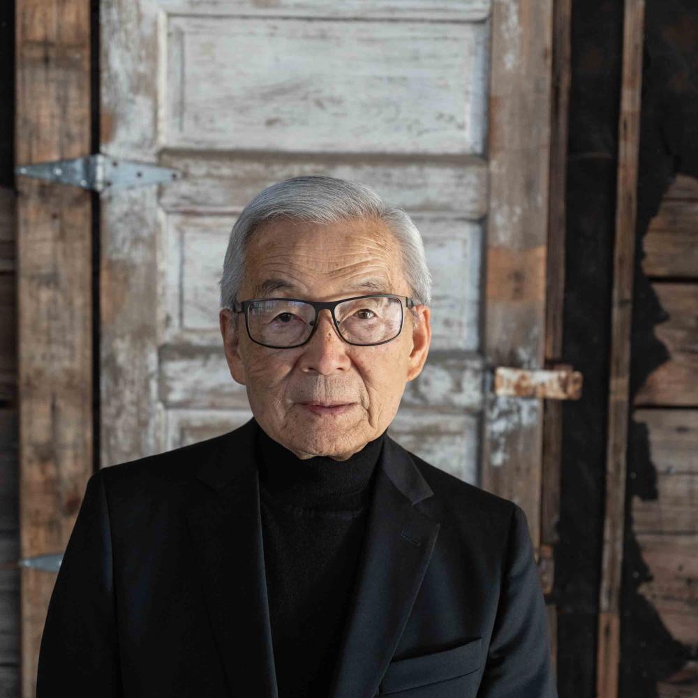 Photo of Sam Mihara standing in front of a barrack door inside the Japanese American National Museum