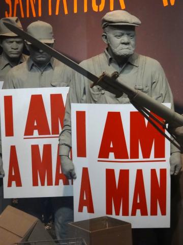 A diorama of strikers holding signs that say I am a man.