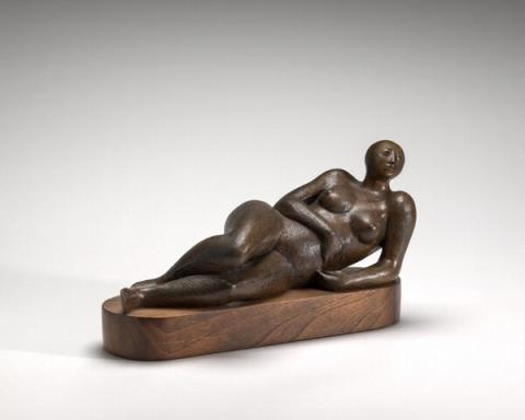 Bronze sculpture of nude female figure reclining on left arm, right arm drapes across waist