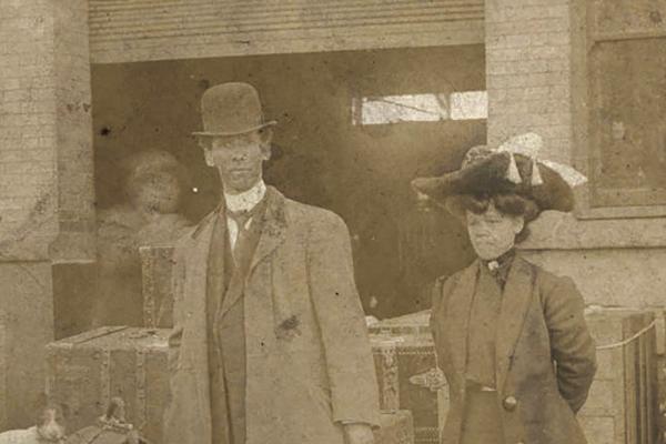 J. Hartford and Lille Belle Armstrong on a train platform with a dog and luggage.
