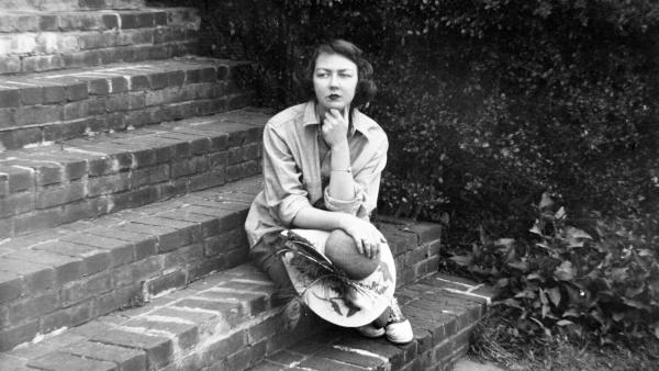 Black and white image of Flannery O'Connor seated on steps