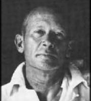 Headshot of cummings, looking directly at the camera, white collared shirt loose and unbuttoned at the top