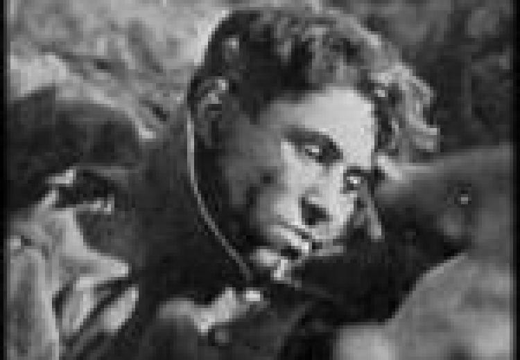 A soldier with his neck in a brace, leaning forward, downcast eyes