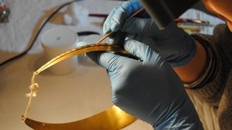 close up of hands working on a piece of gold jewelry