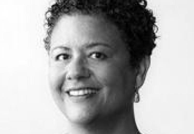 black and white headshot of Alexander, short curly hair, smiling at the camera