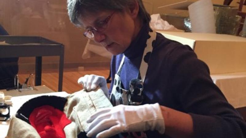 woman wearing gloves examines clothing