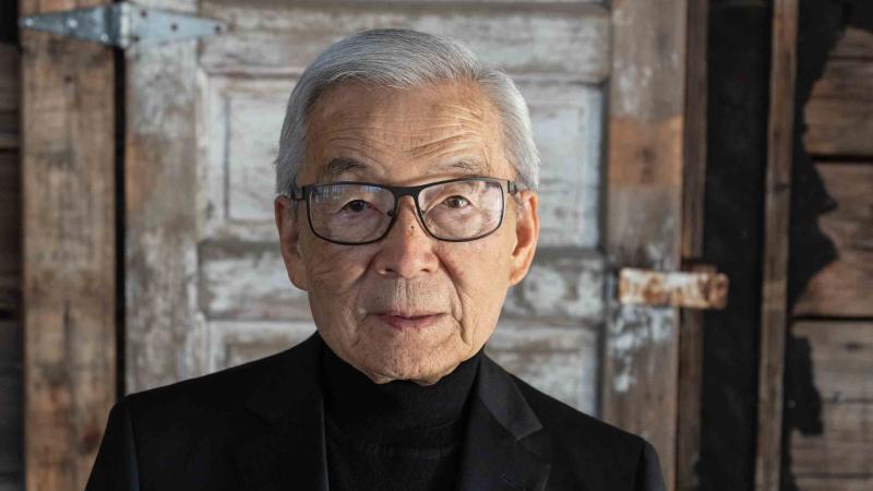 Photo of Sam Mihara standing in front of a barrack door inside the Japanese American National Museum