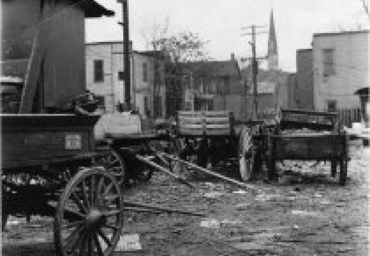 Black and white photograph of a series of abandoned wagons located in Black Bottom neighborhood of Detroit, 1960.