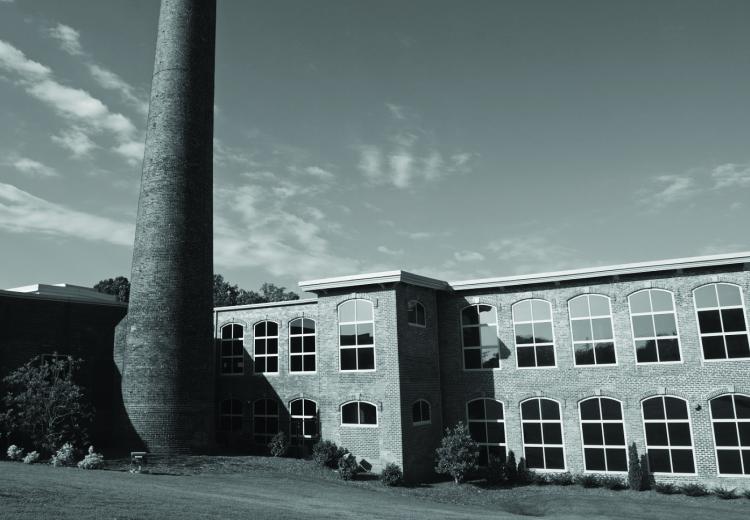 Smokestack and brick building with windows in black and white 
