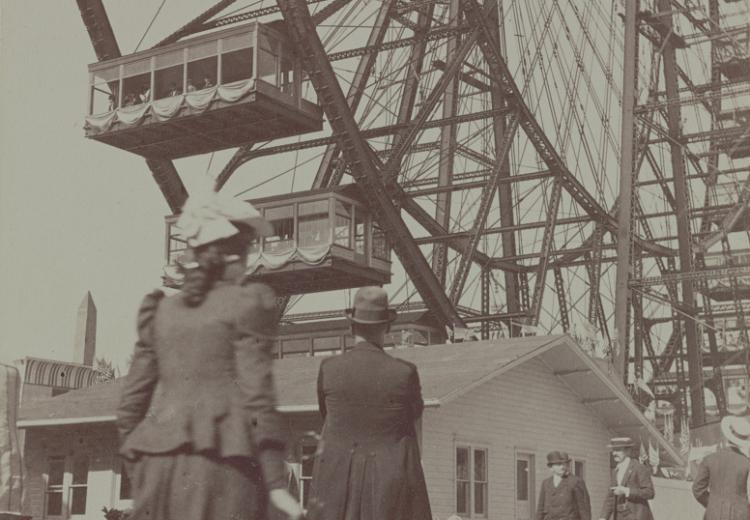 man and woman walking in foreground, Ferris Wheel and other pedestrians in background