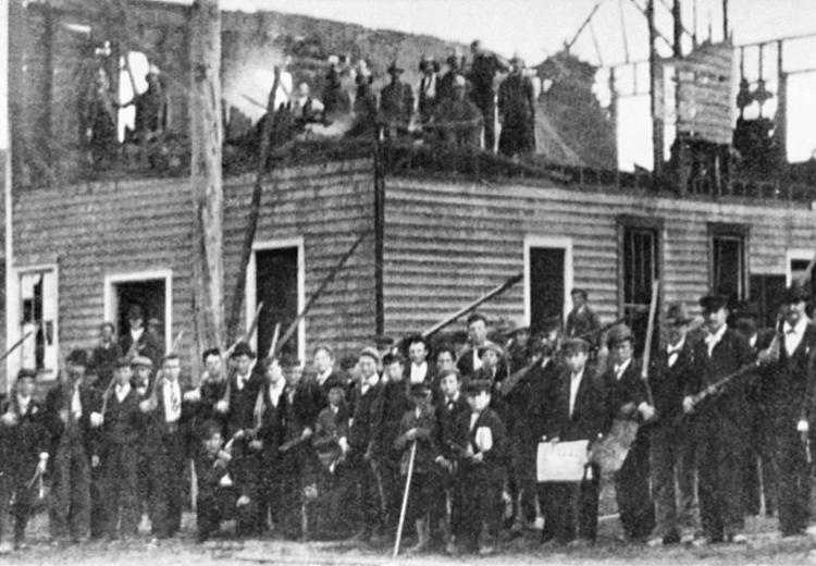 Armed rioters in front of the burned-down "Record" press building.