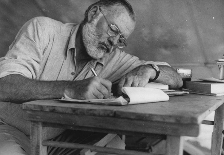 Ernest Hemingway Writing at his campsite in Kenya.