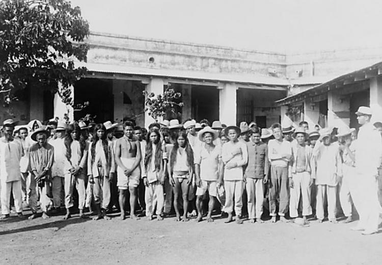 Group of Filipino prisoners of war, posed in courtyard, c. 1900.