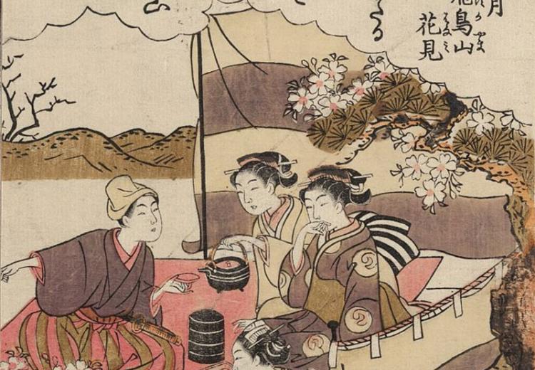Three women and a man having a small tea party beneath blossoming cherry trees.