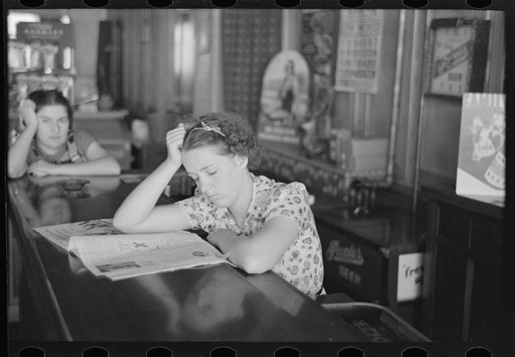 Girl reading newspaper in restaurant bar, Tower, Minnesota